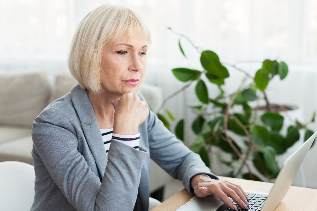 Woman working on a laptop at home, looking focused